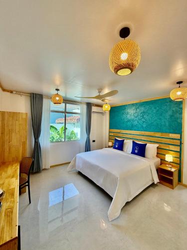 a bedroom with a white bed and a blue wall at Serene Dhigurah in Dhigurah
