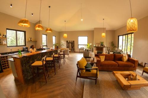 a large living room with a bar and a woman in the kitchen at Huduma Bwindi Lodge in Kisoro