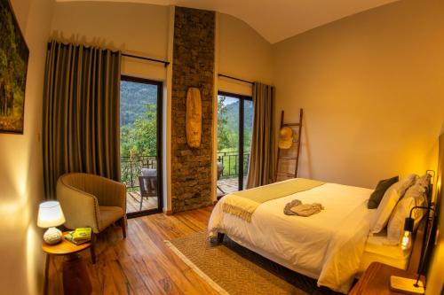 a bedroom with a bed and a chair and a balcony at Huduma Bwindi Lodge in Kisoro