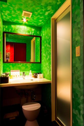 a green bathroom with a toilet and a sink at ホテルR-Adult only-lovehotel in Gotemba
