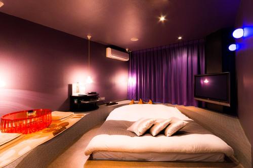 a bedroom with a bed and a tv on the wall at ホテルR-Adult only-lovehotel in Gotemba