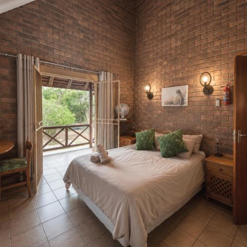 a bedroom with a bed and a brick wall at Dumela Afrika in Marloth Park