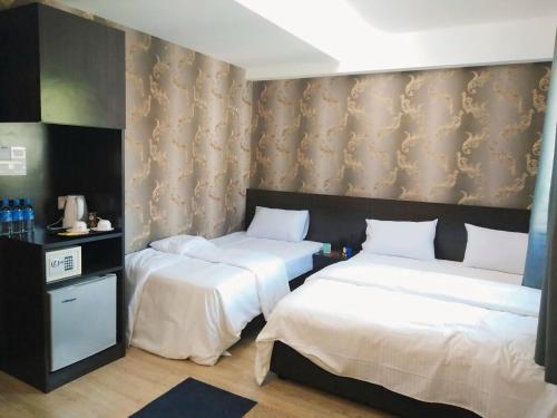 two beds in a hotel room with white sheets at 7 Hotel in Juru