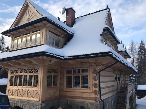 Cabaña de madera con nieve en el techo en Apartament Tatrzański, en Zakopane