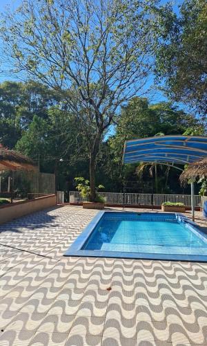 a swimming pool with a blue umbrella and a tree at Cabañas Gonga - Posada turistica in Ciudad del Este