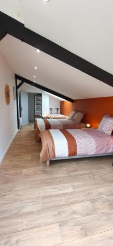two beds in a large room with wood floors at Gîte des Tamaris Maison Chaleureuse proche Circuit in Arnage
