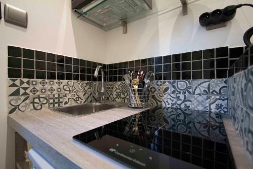 a kitchen counter with a sink and black tiles at Notre Dame Paradis Latin in Paris