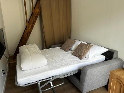 a bed with white sheets and pillows in a room at Le Petit Gaillard in Les Andelys