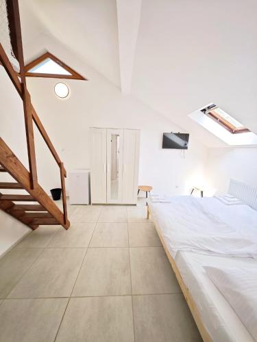 a white bedroom with a large bed and a staircase at Villa Slnava in Banka