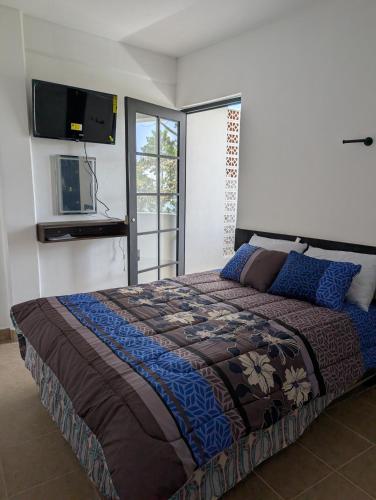 a bedroom with a large bed with a tv on the wall at Hotel de la Montaña in Huautla de Jiménez