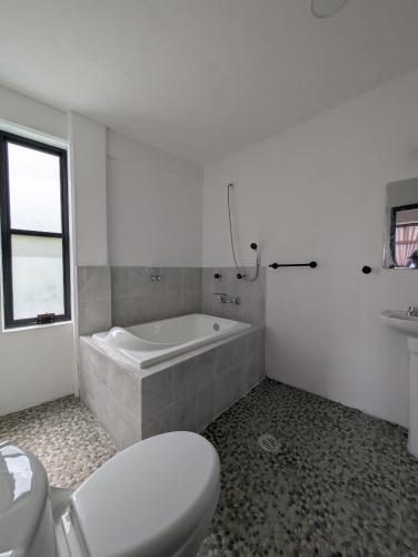 a bathroom with a tub and a toilet and a sink at Hotel de la Montaña in Huautla de Jiménez