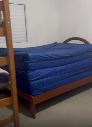 a bed with blue sheets next to a ladder at Chácara sonho meu in Jacutinga