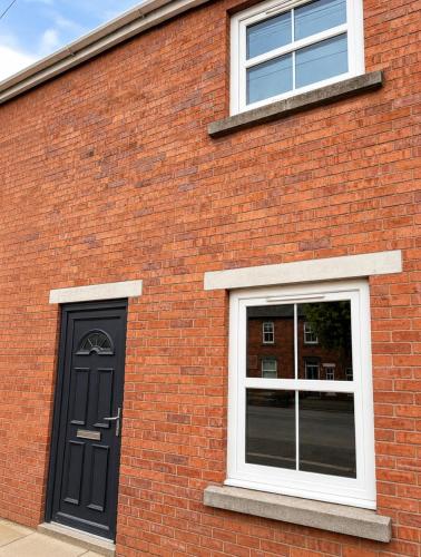 a brick building with a black door and two windows at 11 Netherby Street in Longtown