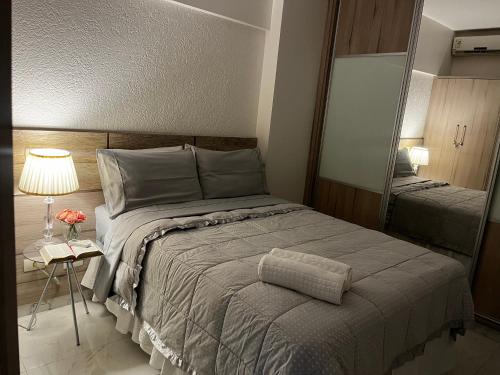 a bedroom with a large bed and a mirror at Apartamento Petúnia 2qto até 3 pessoas Res Unique in Goiânia
