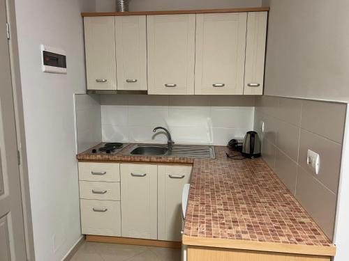 een kleine keuken met witte kasten en een spoelbak bij Thoma's K Studios in Vlorë