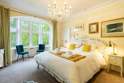 a bedroom with a large white bed and a chandelier at Lindores Bed & Breakfast in Todmorden