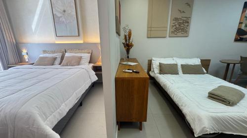 a bedroom with two beds and a wooden table at Namas 406 Niterói - perto da UFF, Barcas e Praias in Niterói