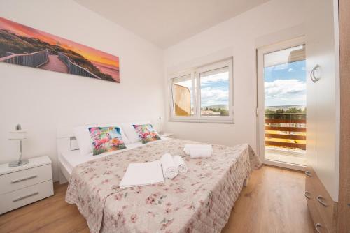 a white bedroom with a bed and two windows at Hotel Riviera in Starigrad