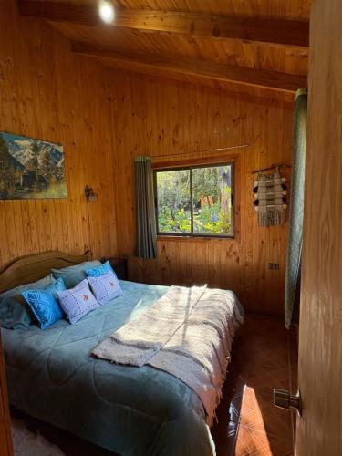 a bedroom with a bed in a wooden cabin at Parcela Peumayen casa 2 in Pucura