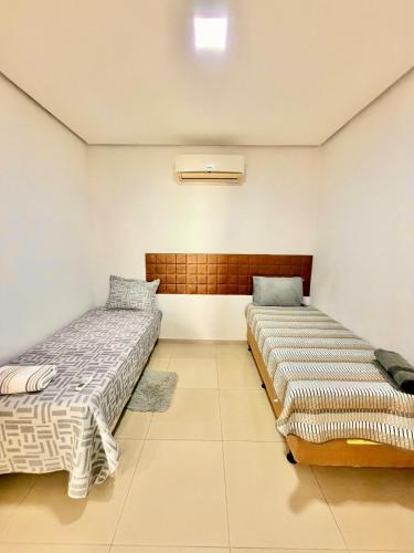 two beds are sitting in a room with at Apartamento de 2 Quartos no Centro in Imperatriz