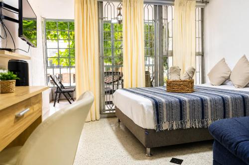 a bedroom with a bed and a living room with a tv at Loft cerca a Laureles, WIFI, cerca metro, con Balcón, GUARDA MALETAS GRATIS!! in Medellín