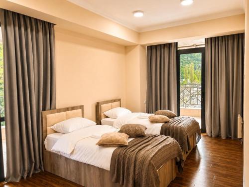two twin beds in a room with a window at Riverside Penthouse in Dilijan in Dilijan