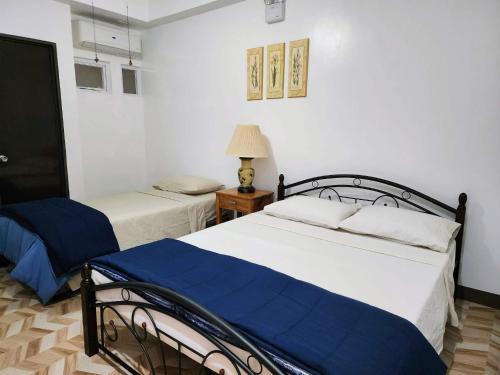 a bedroom with two beds and a table with a lamp at Domus Florum Travellers Inn in Legazpi