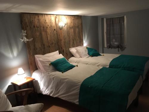 two beds in a hotel room with green pillows at Le Marancènes in Laroque-Timbaut