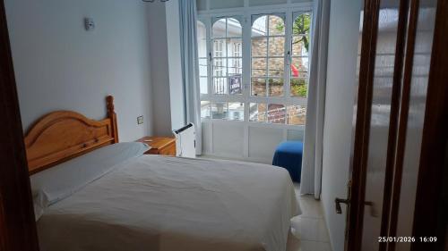 a bedroom with a bed and a large window at Piso casco antiguo in Cedeira