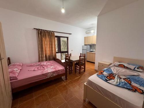 a room with two beds and a dining room with a table at Hotel Gjinaj in Shëngjin