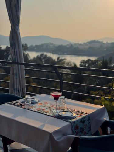 a table with a glass of wine on a balcony at AAJ HAVELI - Pichola Lake Facing Hotel in Udaipur