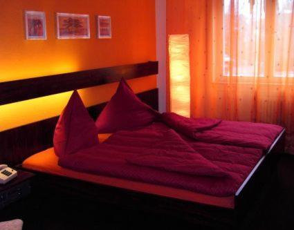 a bed with red sheets in a room with a window at Hotel Dietz in Bopfingen