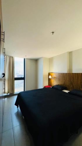 a bedroom with a black bed and a large window at Promoção - Flat em Brasília in Brasília