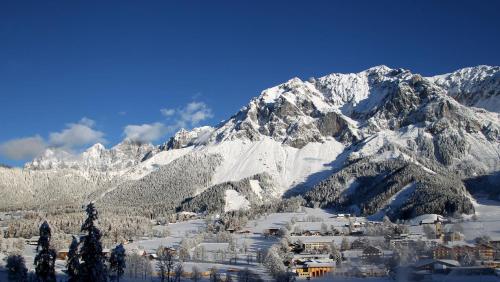 a snow covered mountain range with a village in the foreground at Pension Adlerhorst in Ramsau am Dachstein