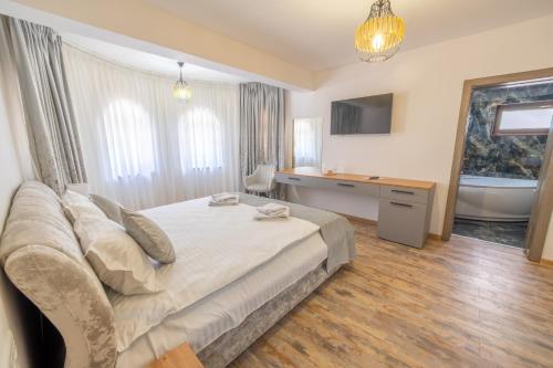 a bedroom with a bed and a bathroom with a tub at Pensiunea Seraris in Voineasa