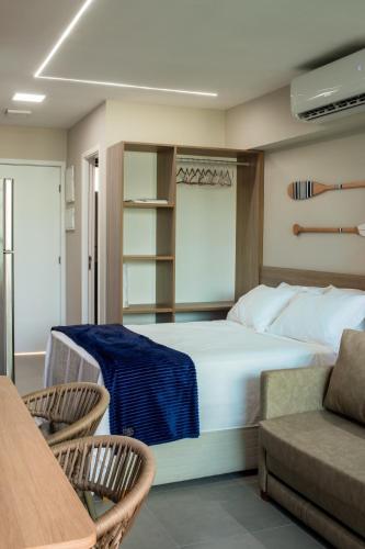 a bedroom with a bed and two chairs and a couch at Nomar 208 pe na areia na Praia dos carneiros in Tamandaré