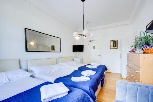 two beds in a room with a mirror on the wall at Boltons Residence Collection Hotel London in London