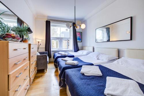 a bedroom with three beds with blue sheets at Boltons Residence Collection Hotel London in London