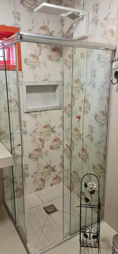 a shower with a glass door with floral wallpaper at Chalé Vale das Montanhas in Timbe do Sul