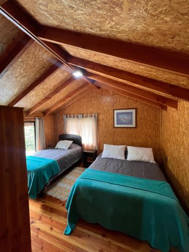 two beds in a room with wooden ceilings at Parcela Peumayen casa 3 in Pucura