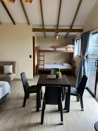 a dining room with a table and chairs and a bunk bed at Bosque Encantado Cabañas chalet in Guatapé