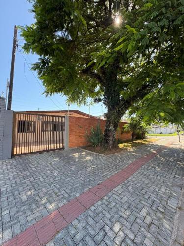 a tree in front of a brick fence and a tree at Quarto Aconchego in Guaratuba