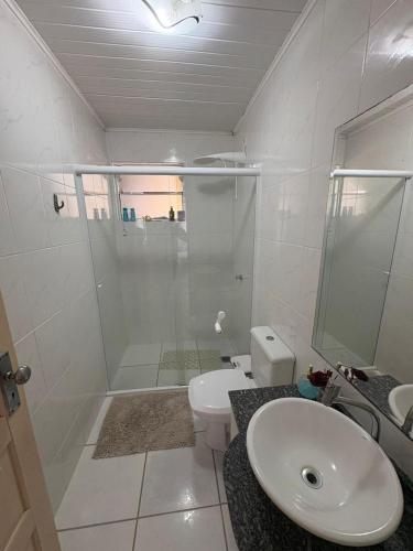 a bathroom with a shower and a toilet and a sink at Quarto Aconchego in Guaratuba