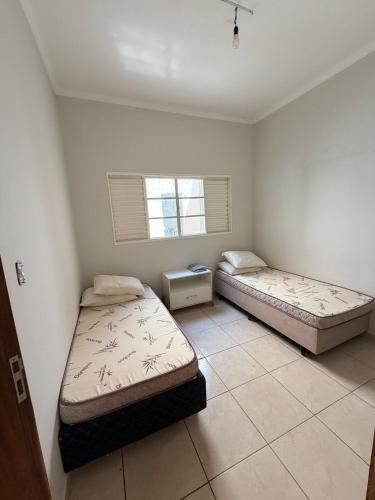two beds in a room with a window at Casa Cambuí Molina in Franca