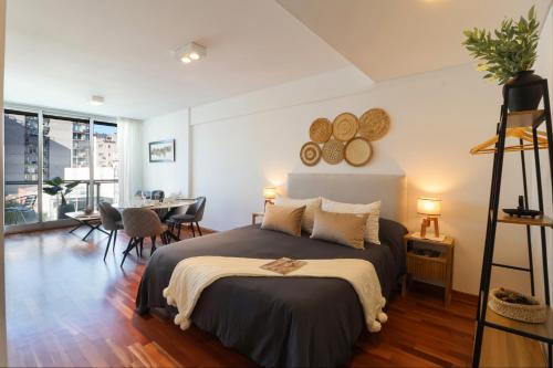 a bedroom with a large bed and a dining room at SkyPort Olivos Vista al Río, Rooftop y Piscina Cubierta in Olivos