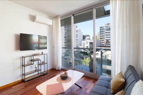 a living room with a couch and a large window at SkyPort Olivos Vista al Río, Rooftop y Piscina Cubierta in Olivos