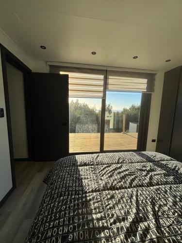 a bedroom with a large bed and a large window at Paraisopingueral in Dichato