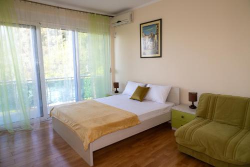a bedroom with a bed and a couch and a window at Blue Horizon Villa DV in Dobra Voda