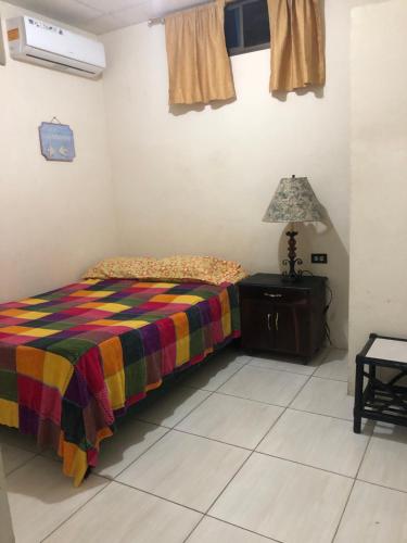 a bedroom with a bed with a colorful blanket and a lamp at hospedaje Maluli suite girasol in Santa Elena