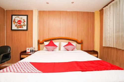 a bedroom with a large bed with red and white pillows at Super OYO Naomi Heritage in Surabaya